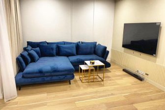 Duży granatowy narożnik z poduszkami w małym salonie z telewizorem