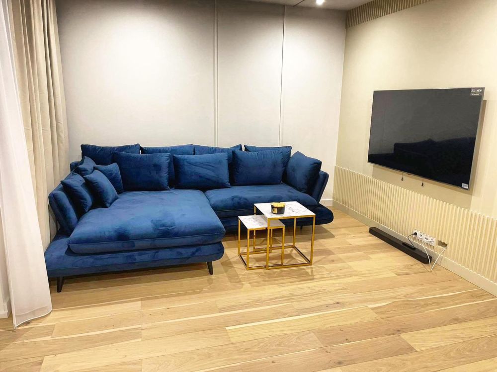 Duży granatowy narożnik z poduszkami w małym salonie z telewizorem