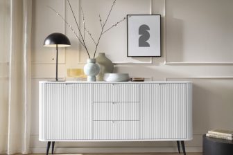 Szeroka komoda biała frezowana na wysokich nogach